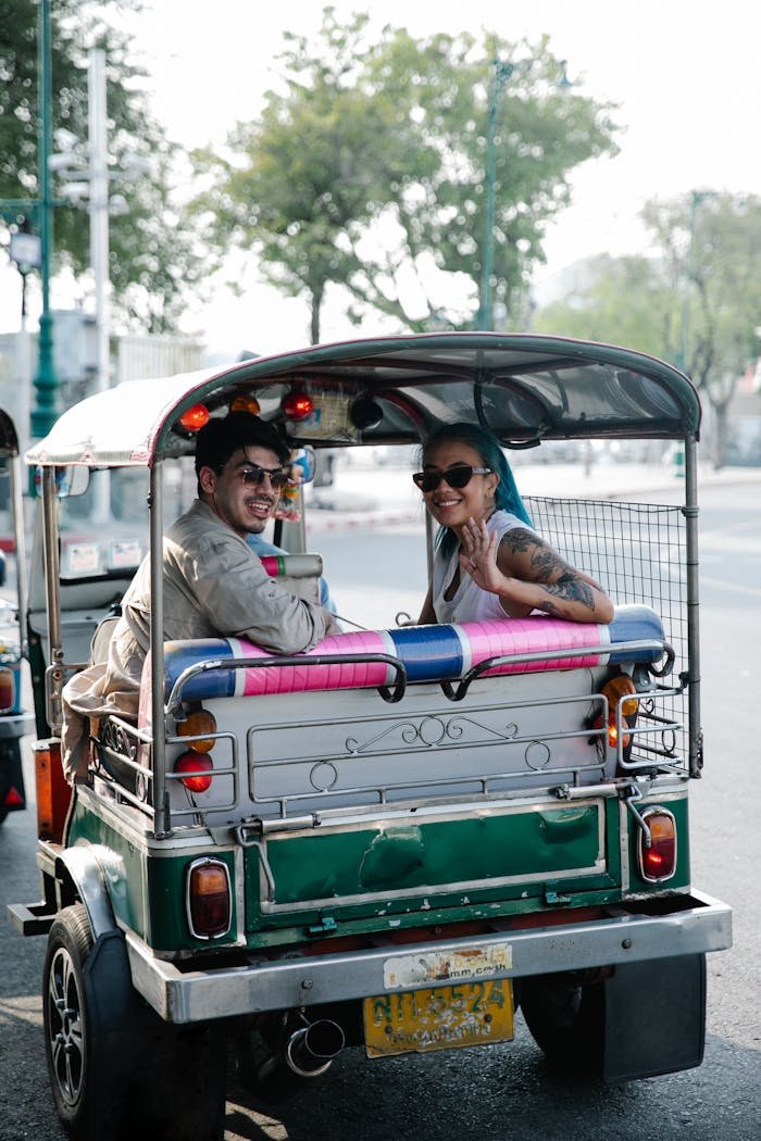 Smiling couple riding in a tuk-tuk on a sunny city day, filled with joy and adventure.